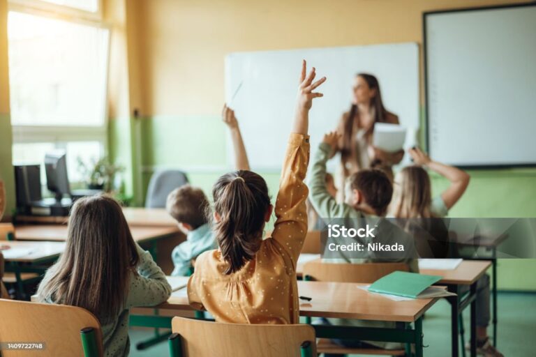 Students raising hands while teacher asking them questions in classroom